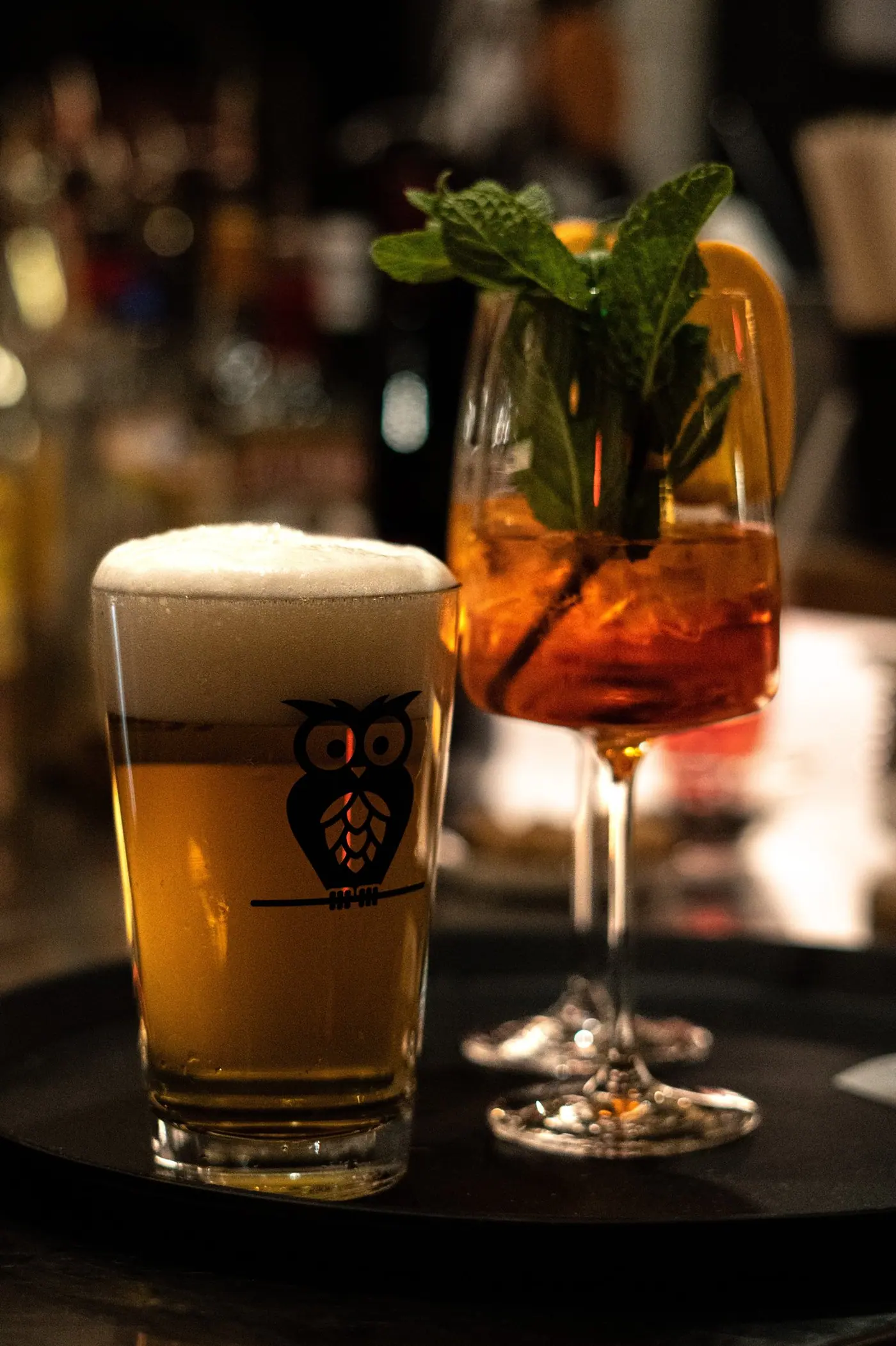 Ein frisch gezapftes Bier im Eulenglas und ein Aperol Spritz mit Minze auf einem Tablett